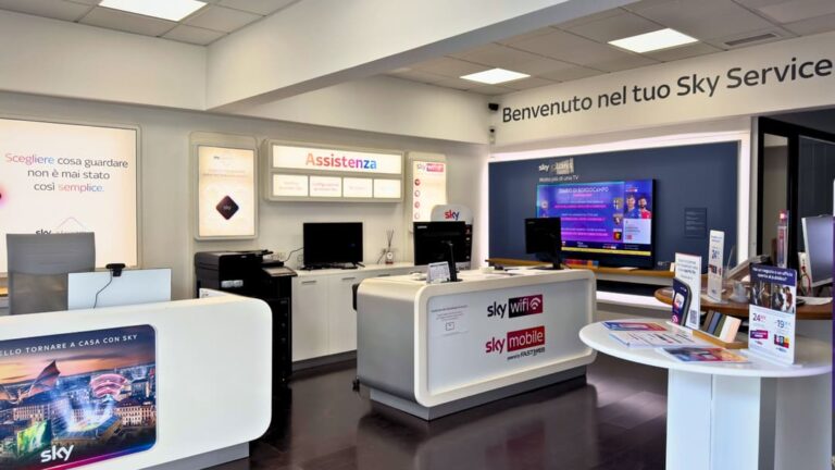 Interno di un negozio Sky Service moderno e ben illuminato, con desk e schermi promozionali.